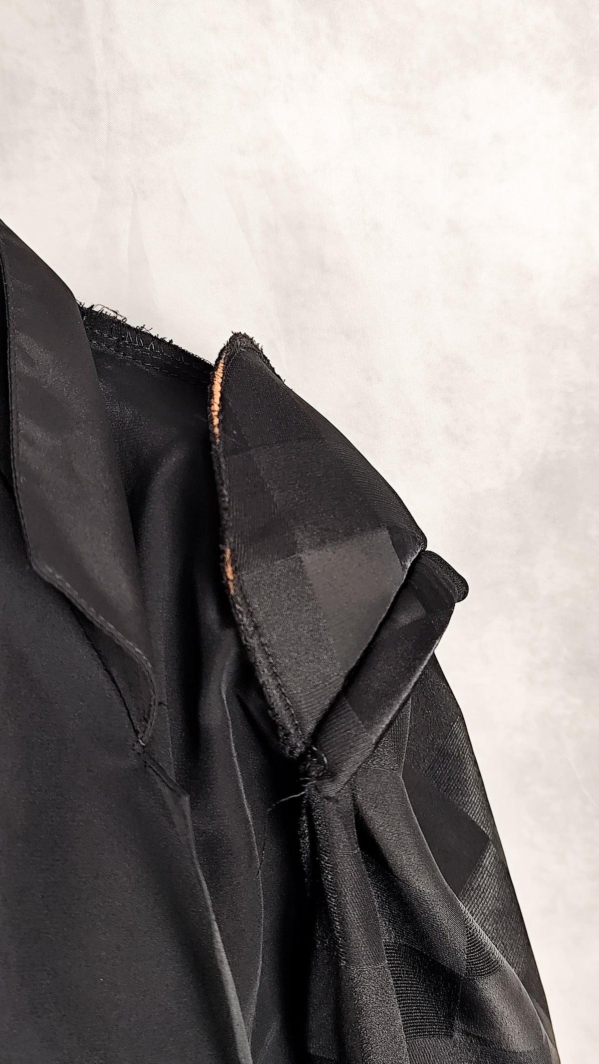 Close up of a shoulder pad of a black patterned sheer blouse from the 90's with a checkered design, for sale at Faceless Queen store. 