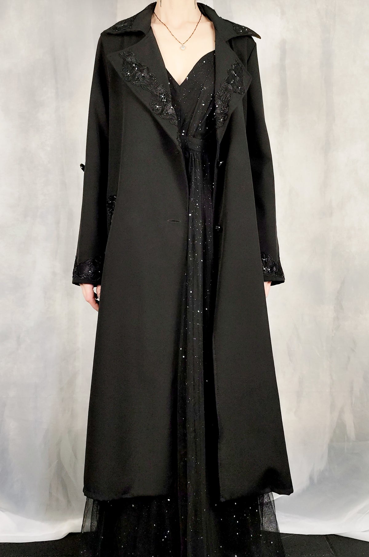Front view of a woman wearing an elegant balck trench coat over an evening dress.