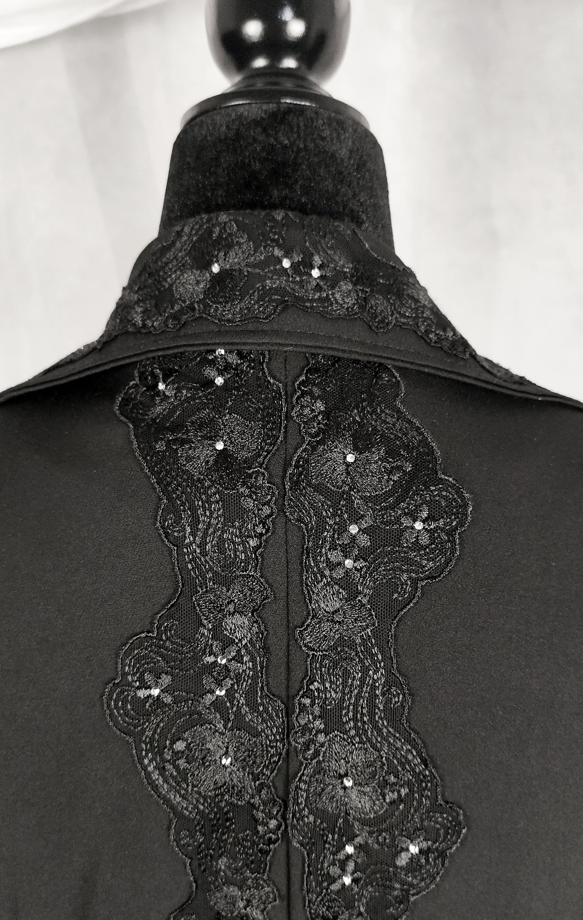 Black lace and sequin embellished collar detail on a black trench coat form mannequin.