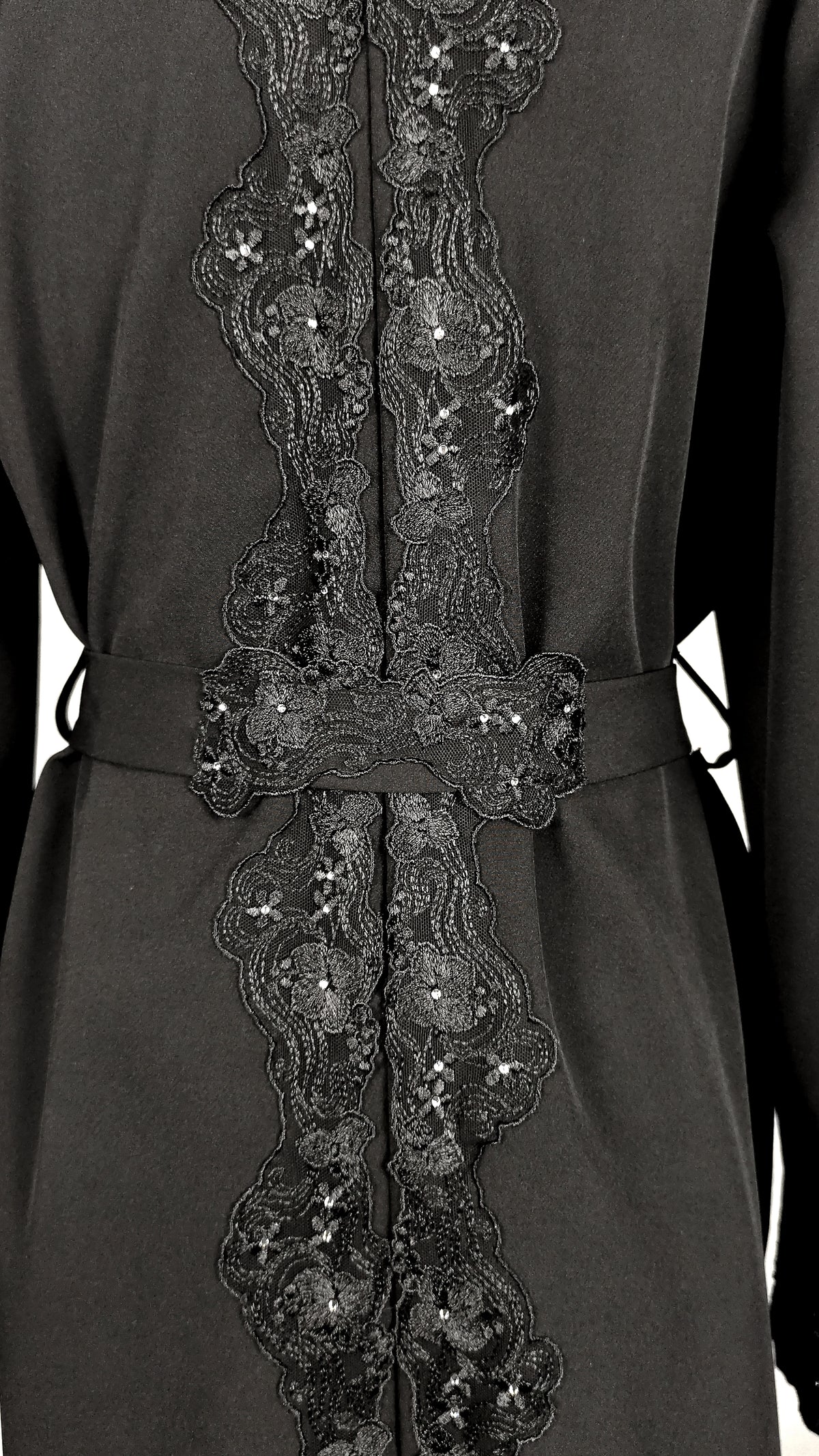 Back of an embellished black trench coat with belt. 