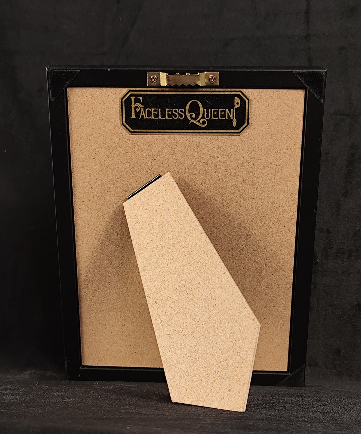 Back of frame with a black and golden "Faceless Queen" tag.