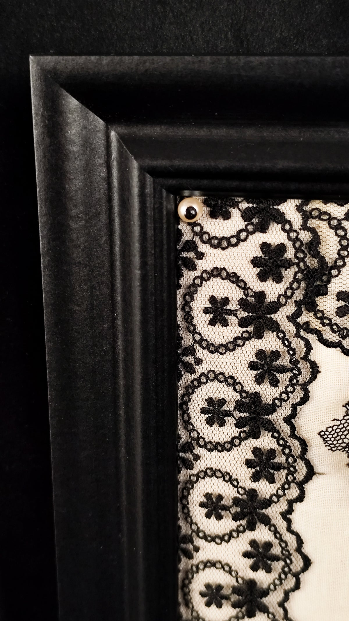 Close-up of gothic frame, featuring  faux-pearl and black lace.