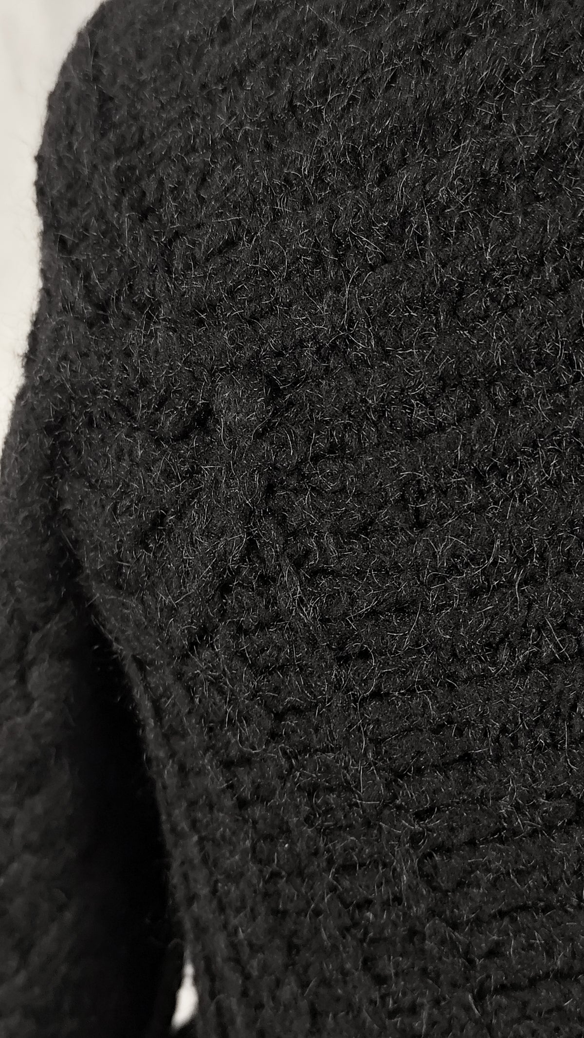 Close-up of a black textured knit cardigan, showing the detailed pattern.