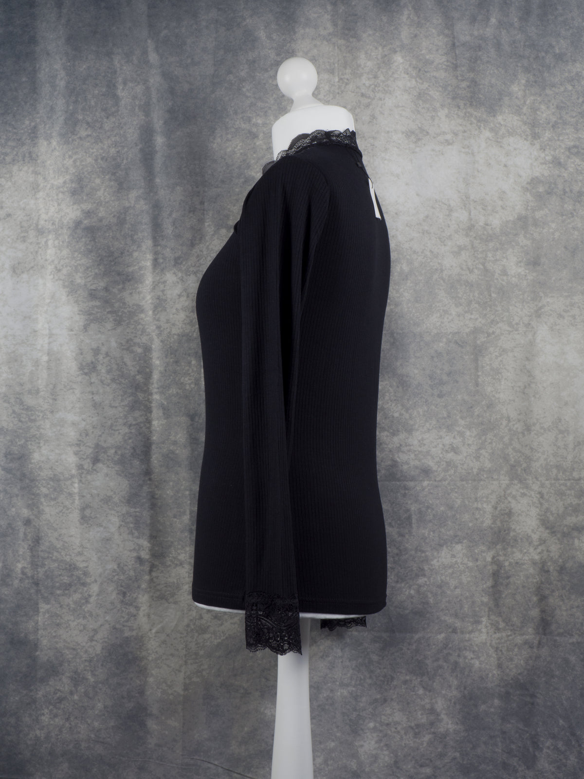 Side view of a black Long sleeve top with lace collar and lace cuffs. Gothic aesthetic.