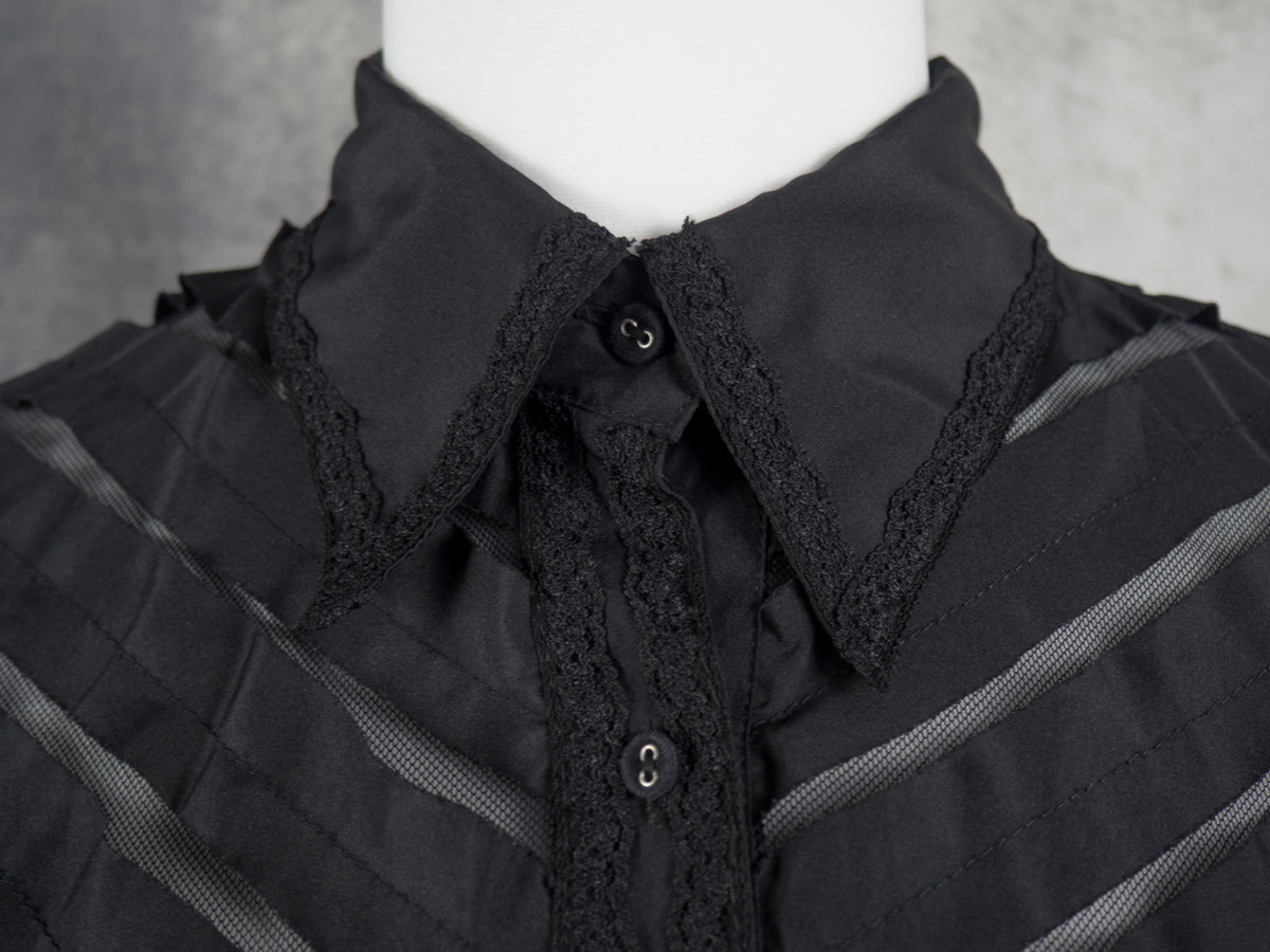 A close-up of a black gothic-style blouse on a white mannequin torso, featuring a high collar with black lace trim, a buttoned front, and subtle horizontal textured stripes.