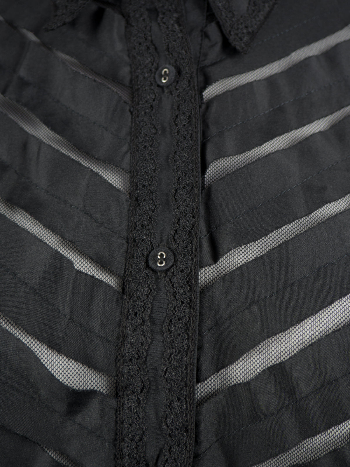Close-up of a black button-front shirt with a textured striped pattern and a central lace placket.