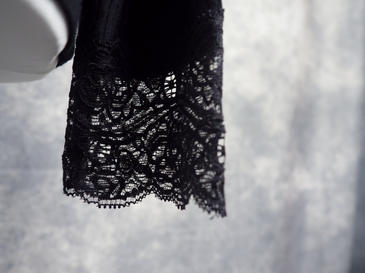 Close-up of a lace cuff from a long-sleeve ribbed knit black top.
