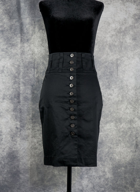 A black high-waisted pencil skirt with a prominent vertical row of dark buttons down the front, displayed on a black dress form against a textured gray background.