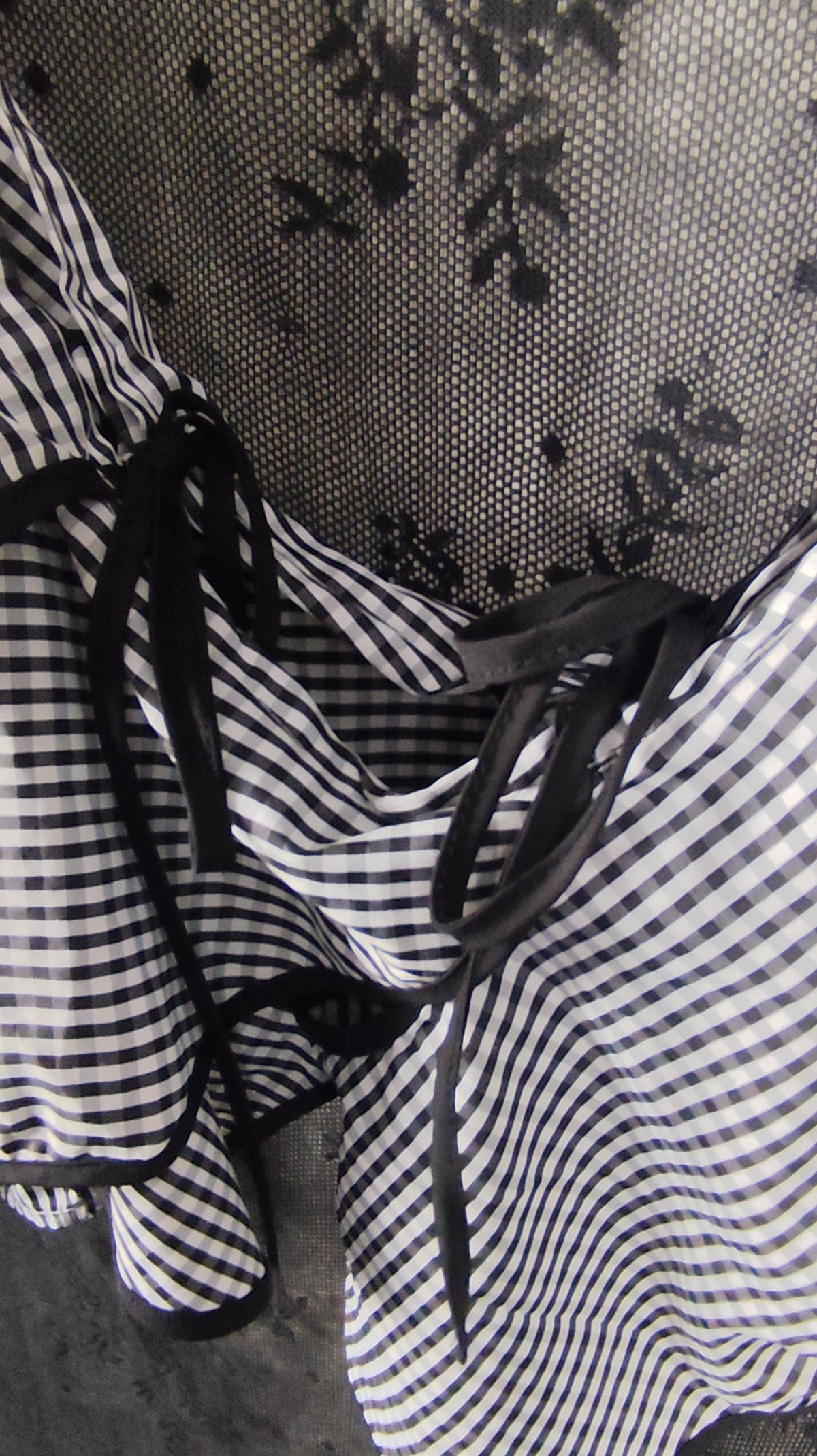 Black and white checkered ruffled sleeve with black ribbon ties, shown in a close-up view.