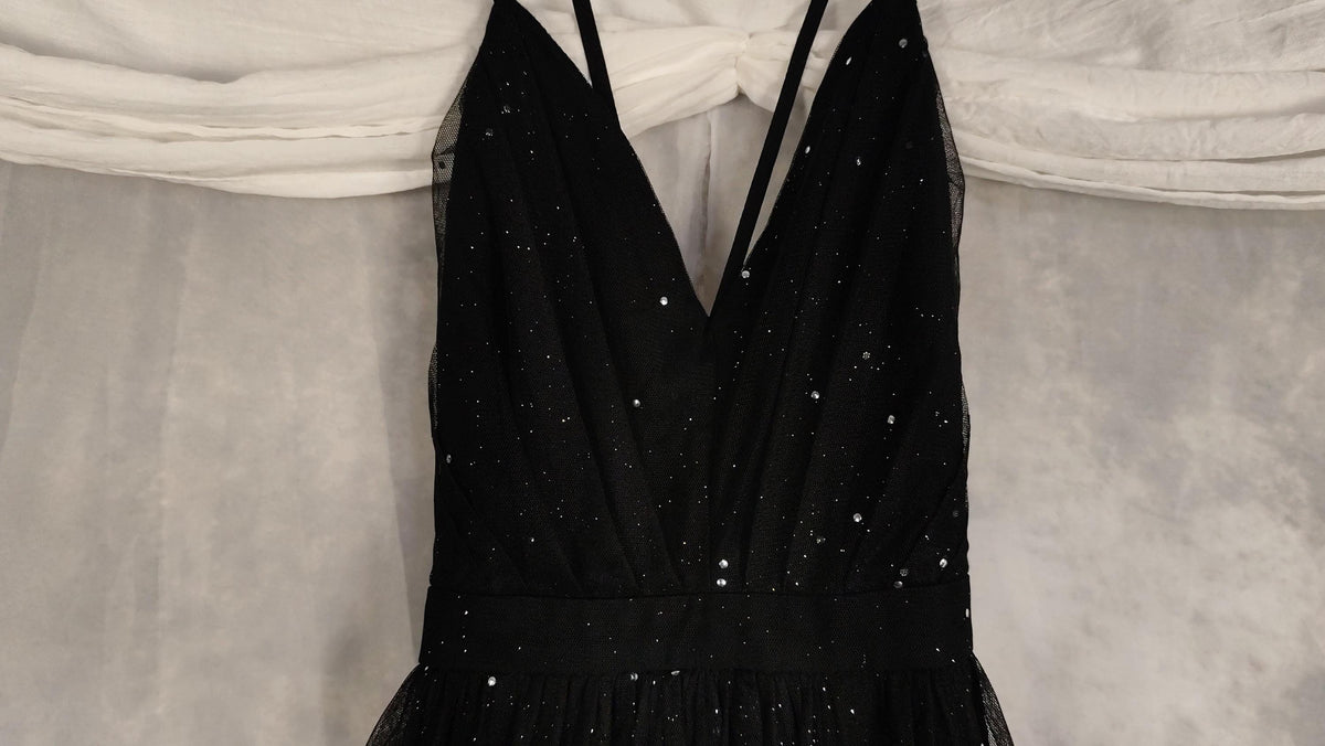 A sweetheart neckline dress with subtle silver glitter sparkles, hanging against a draped white fabric backdrop.
