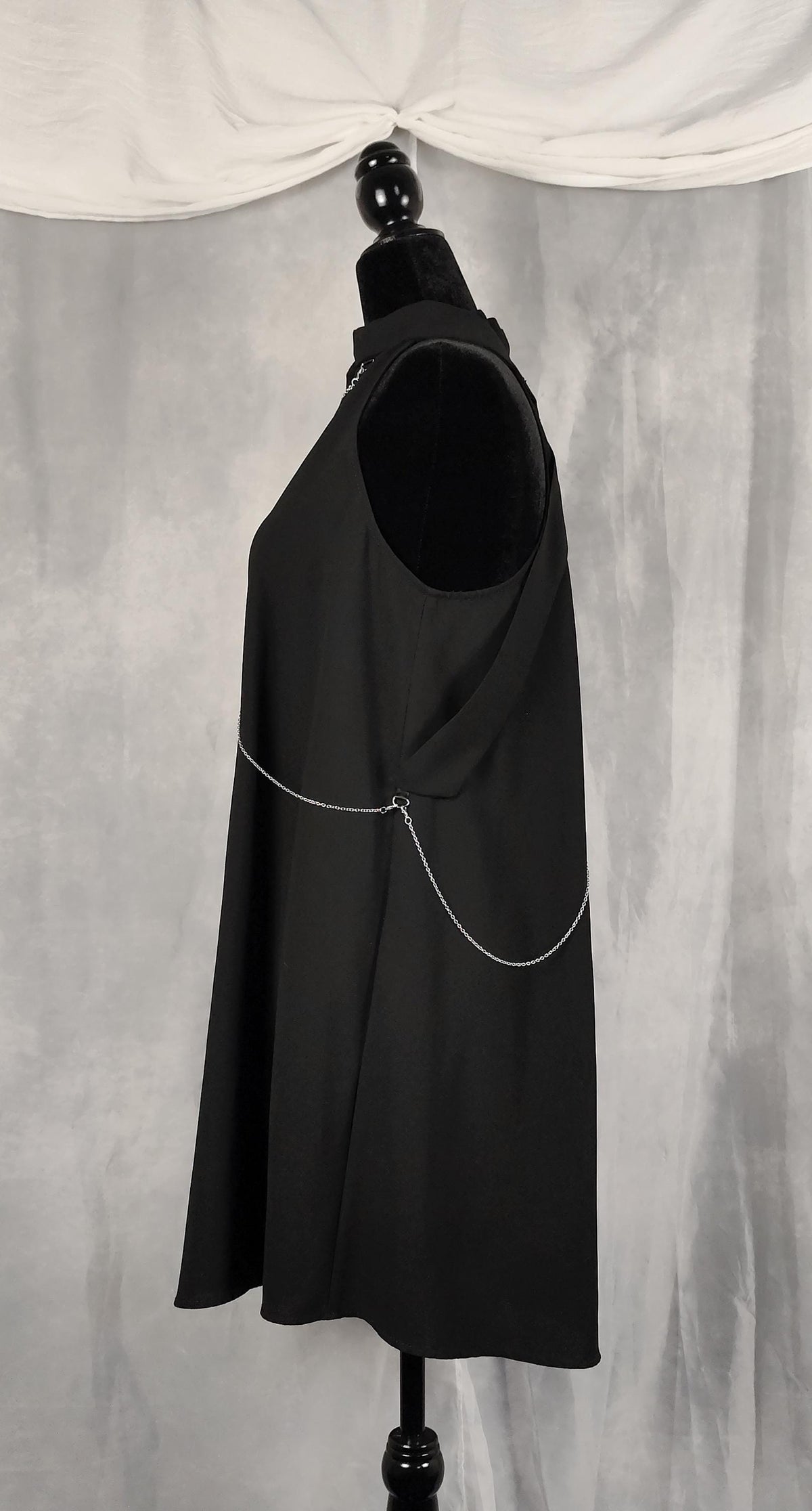 Side view of black tunic with removable chains on front and back.