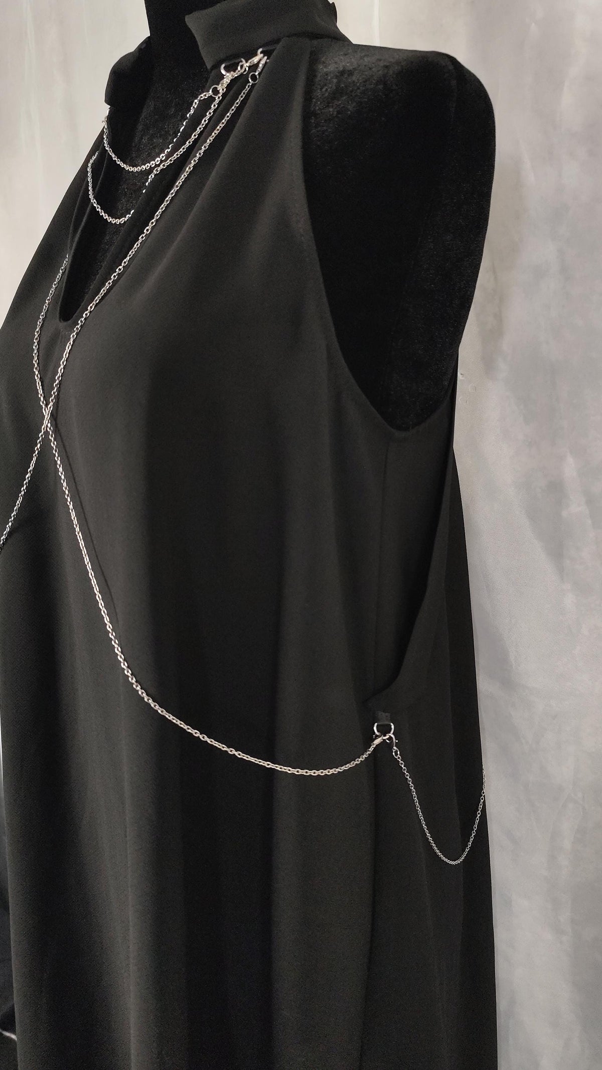 Close-up of front and side of a black tunic with removable chains on the collar, chest and back.