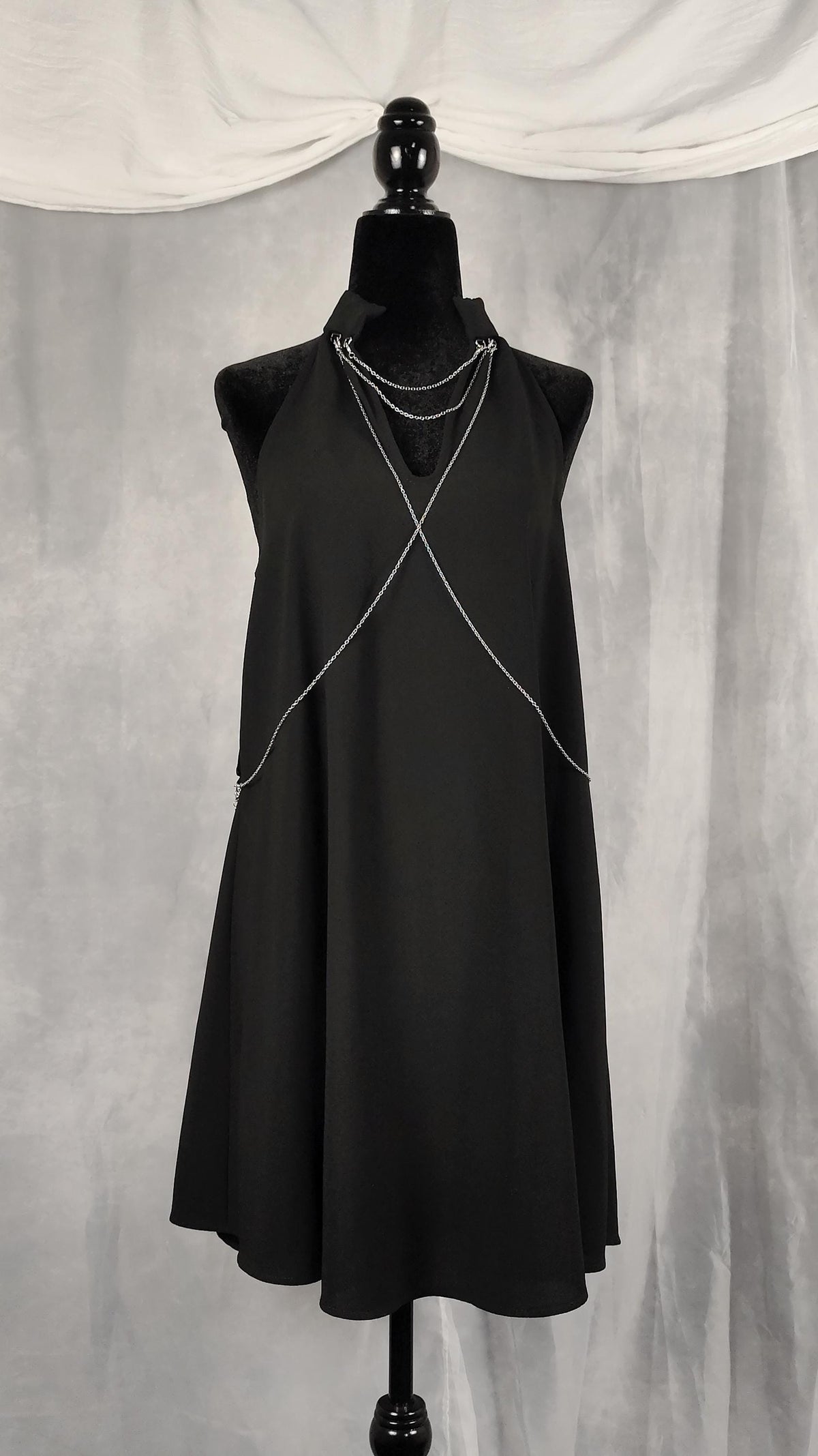 Front view of black tunic with removable chains on the collar and chest.