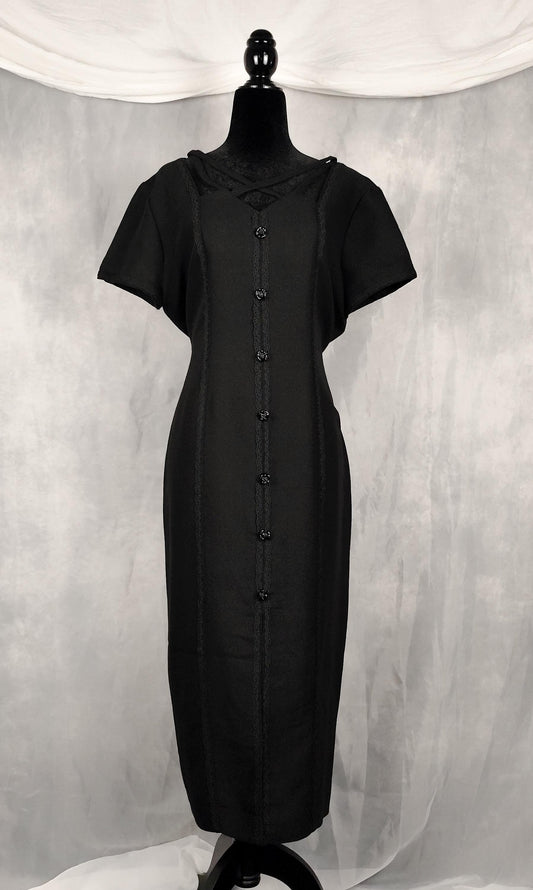 Front view of a black short-sleeve vamp midi dress displayed on a black mannequin against a gray draped fabric backdrop.
