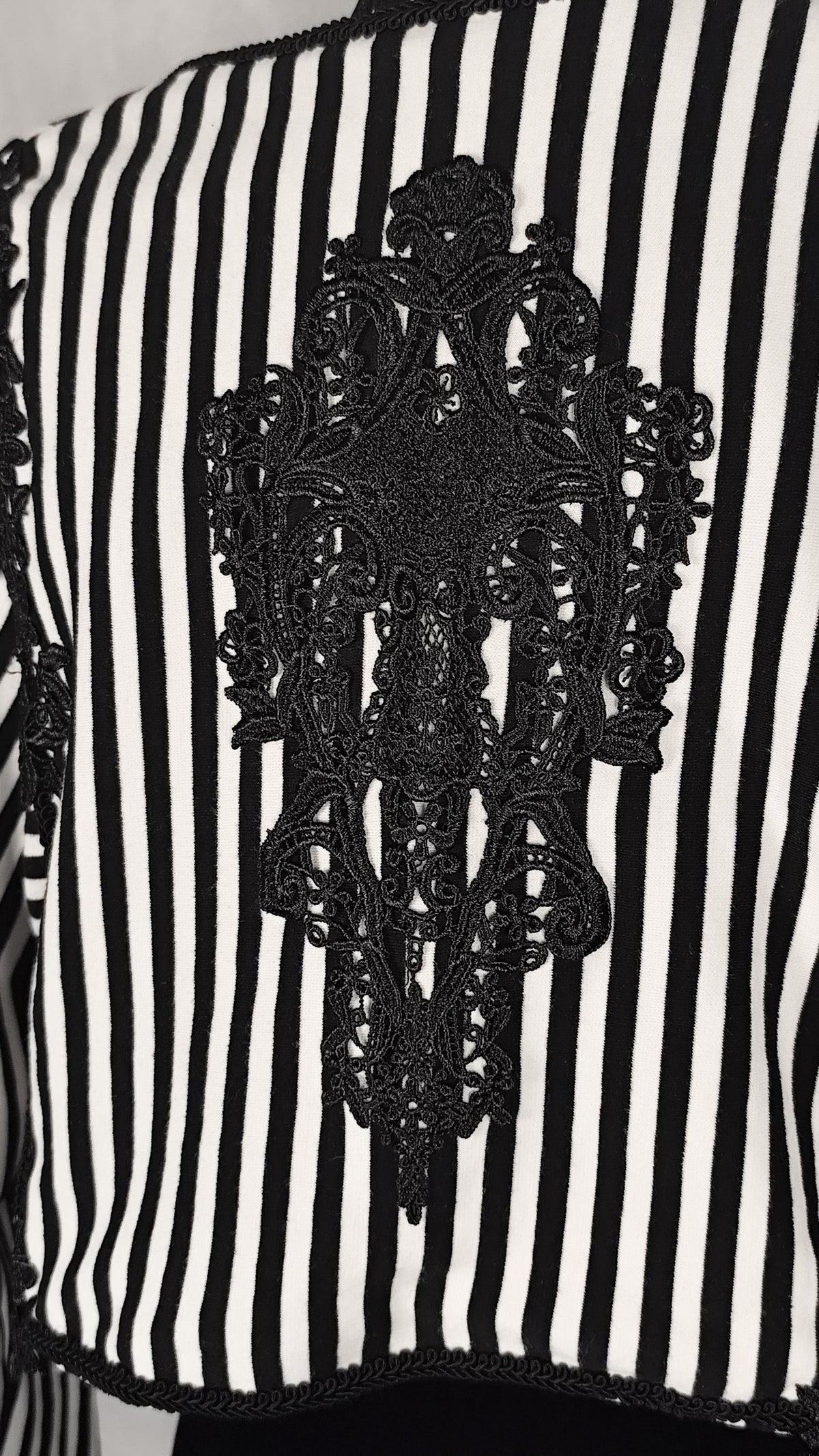 Black and white vertically striped bolero with a large black embroidered lace applique motif in the center.