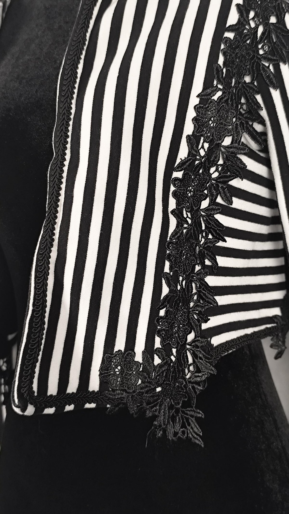 Close-up of a black and white striped bolero with black floral lace trim along the edge.