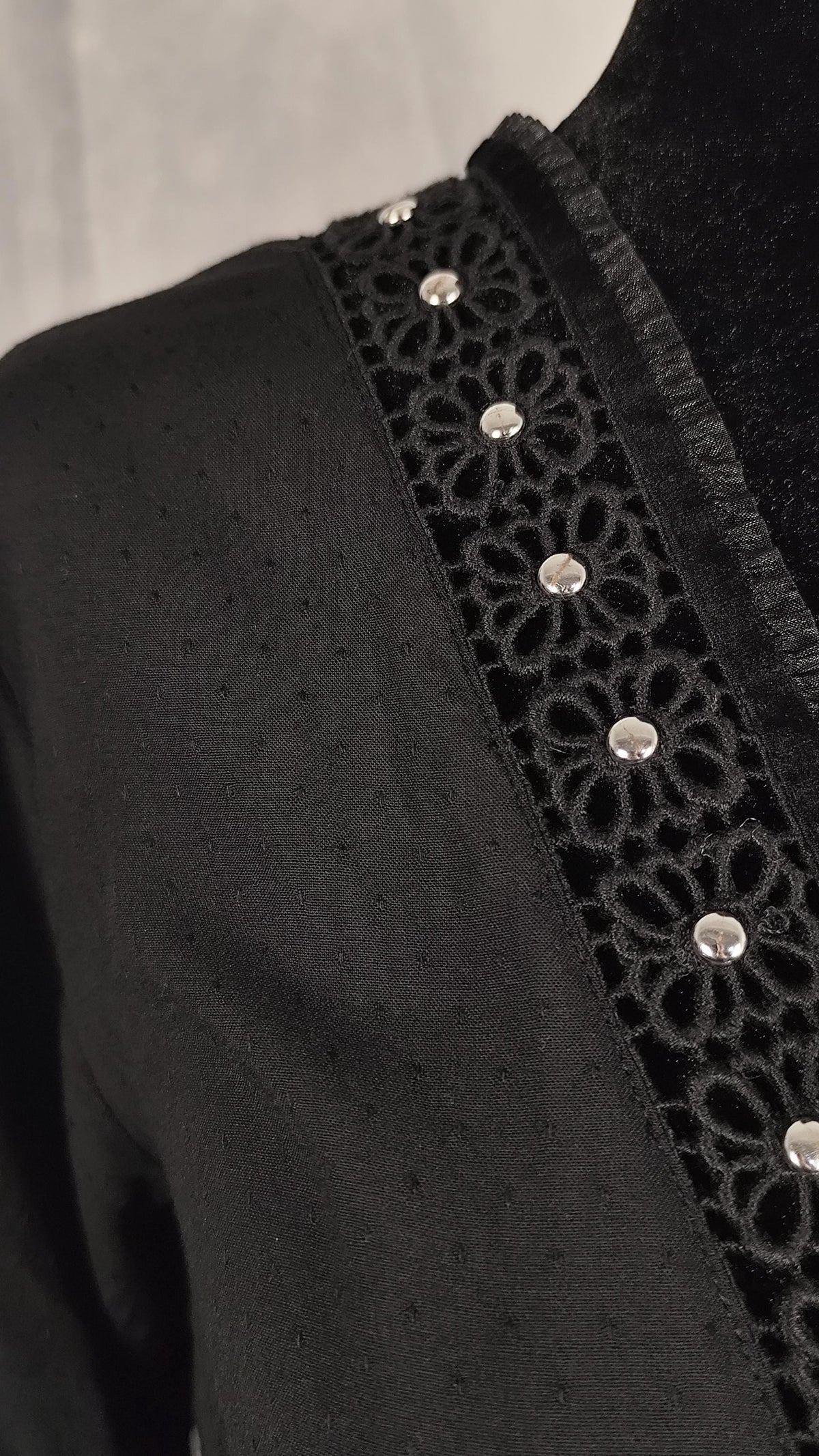 Detail from the V-neckline and sleeve cuffs, trimmed with velvet and tulle of a black wrap dress.