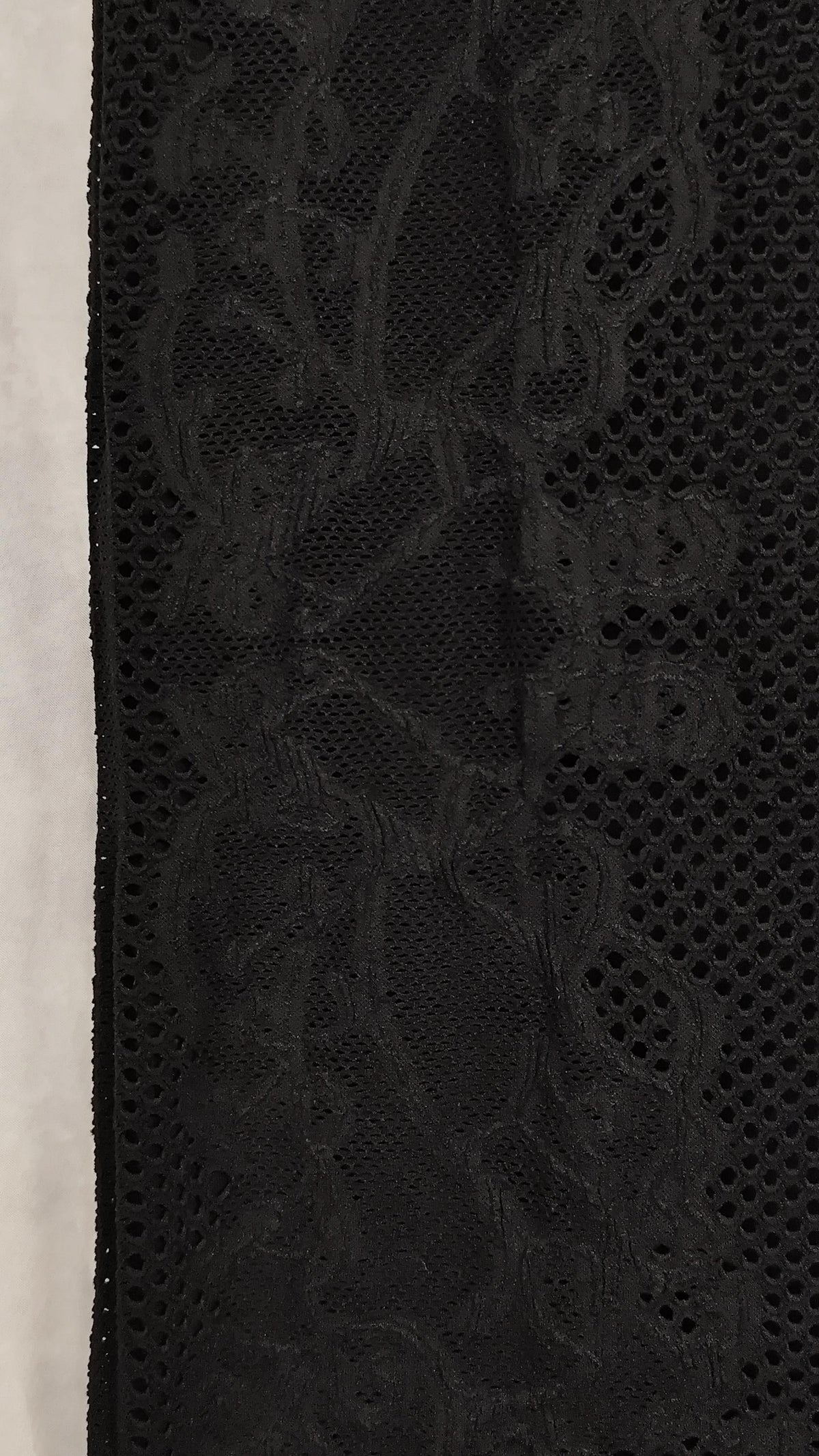 Close-up of a black sheer mesh dress with an intricate floral lace overlay pattern.