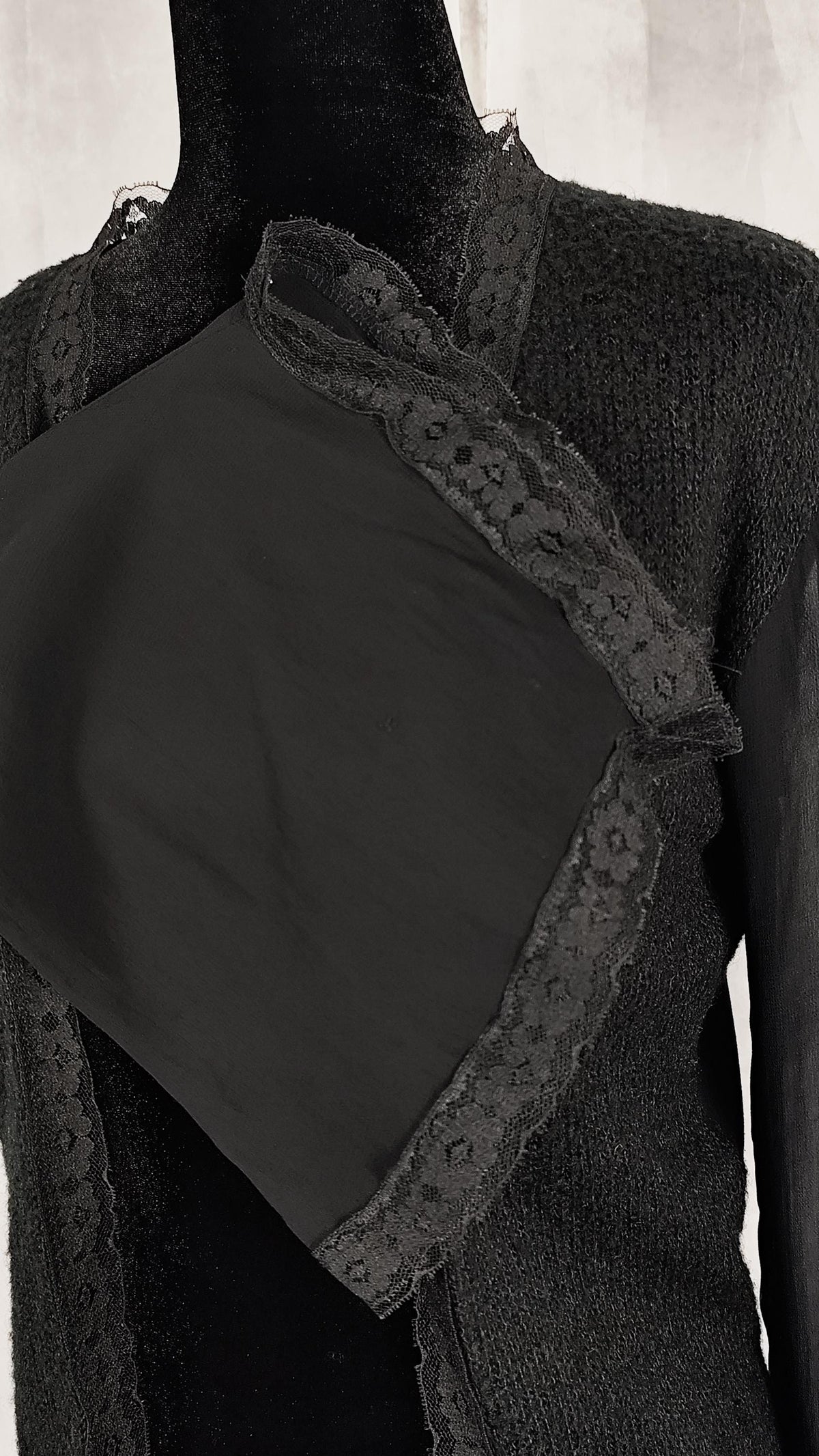 Close-up of lace trimmed sleeve from a delicate black cardigan.