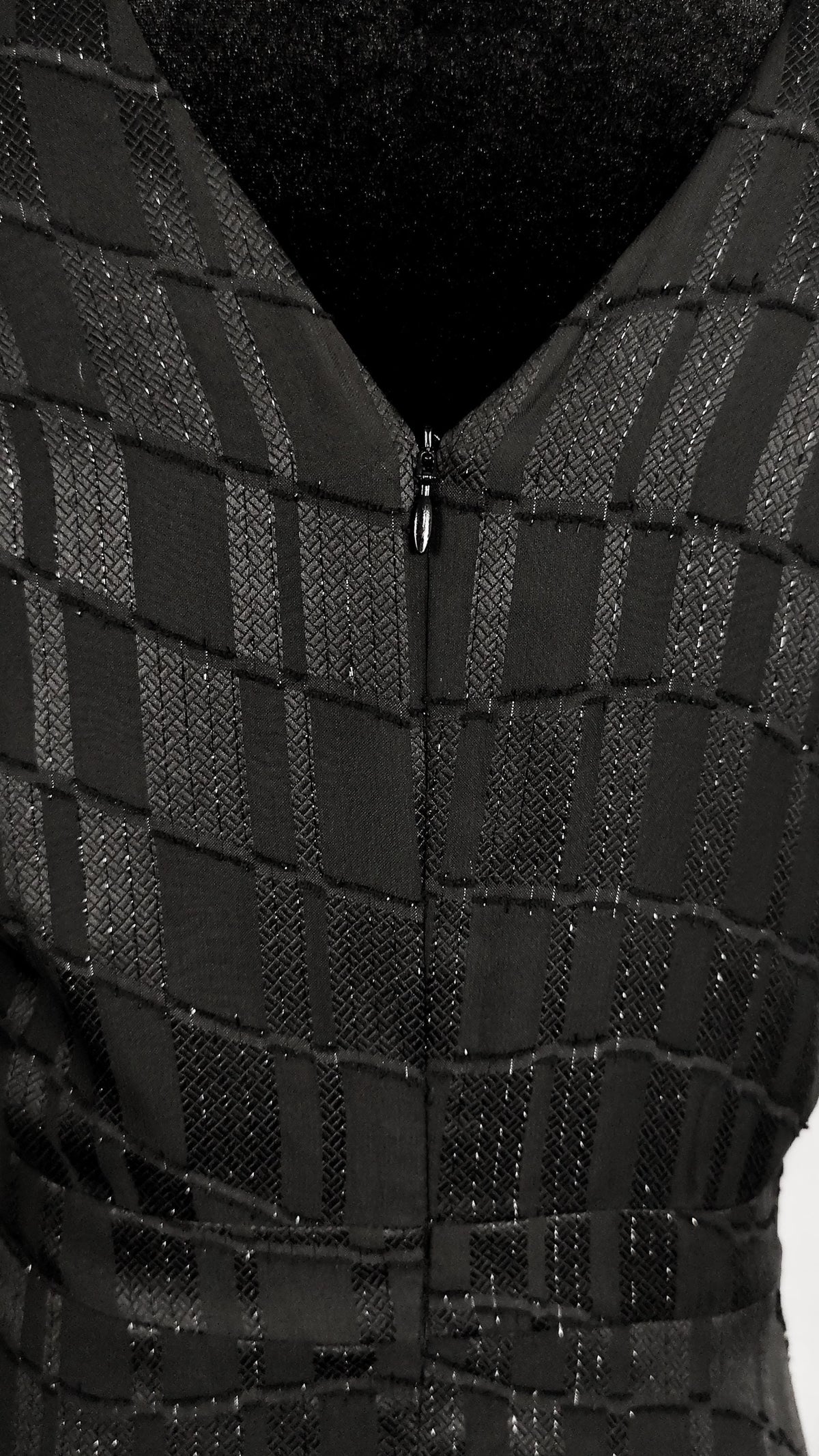 Close-up of a black textured dress with a geometric checkered pattern and a back hidden zipper.