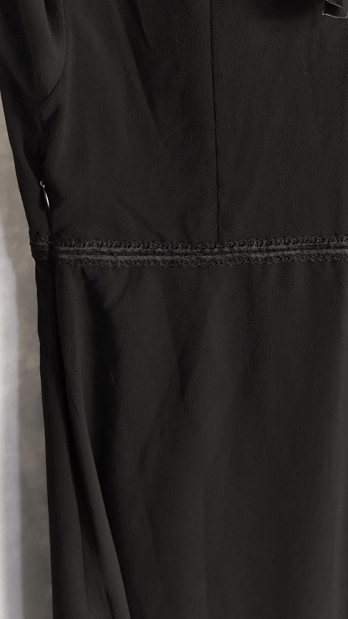 Close-up of a black dress, showing a seam and textured horizontal stitching detail.