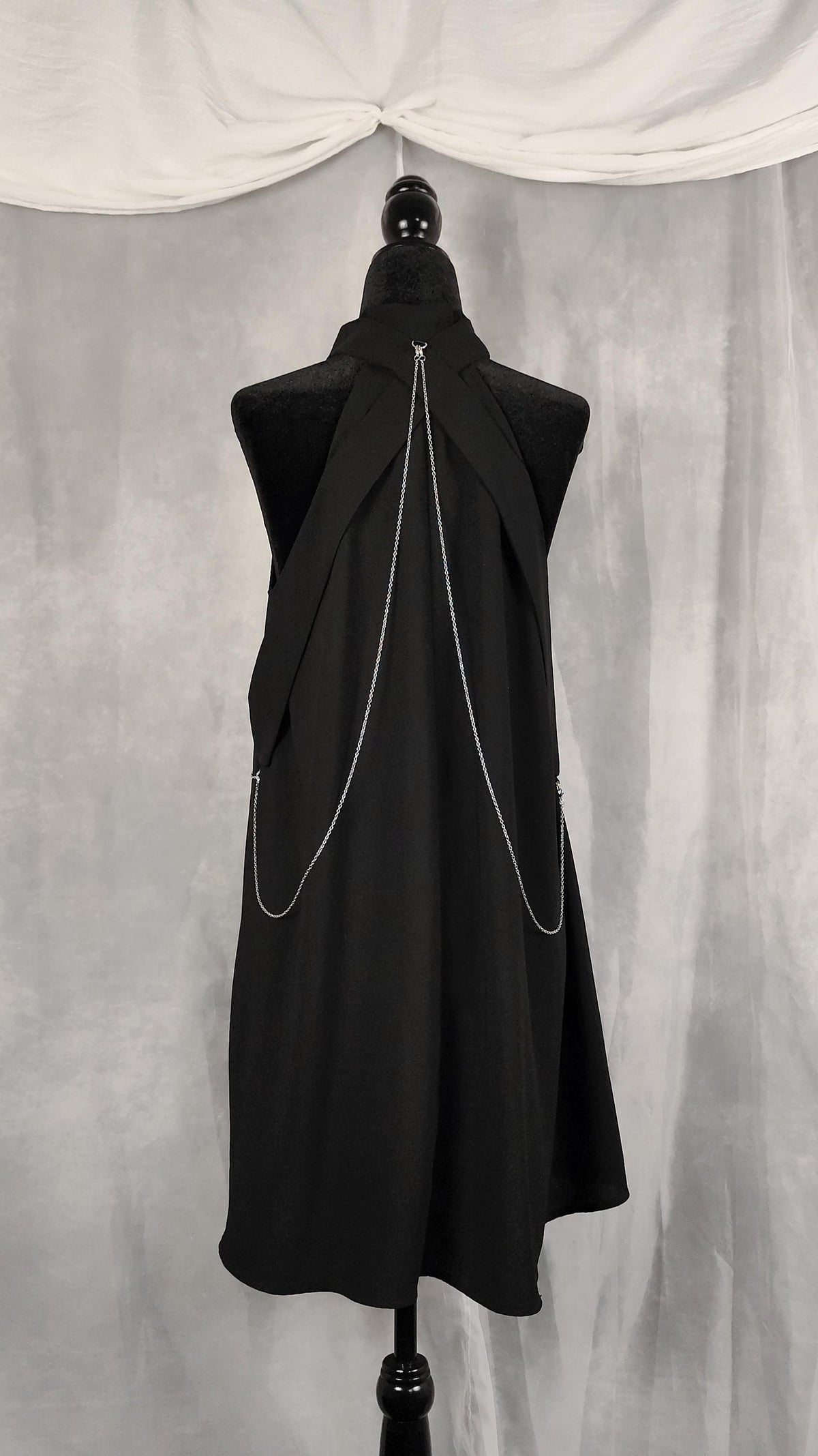 Back view of black tunic with removable chains from the collar to the waist, and straps from the collar to the waist.