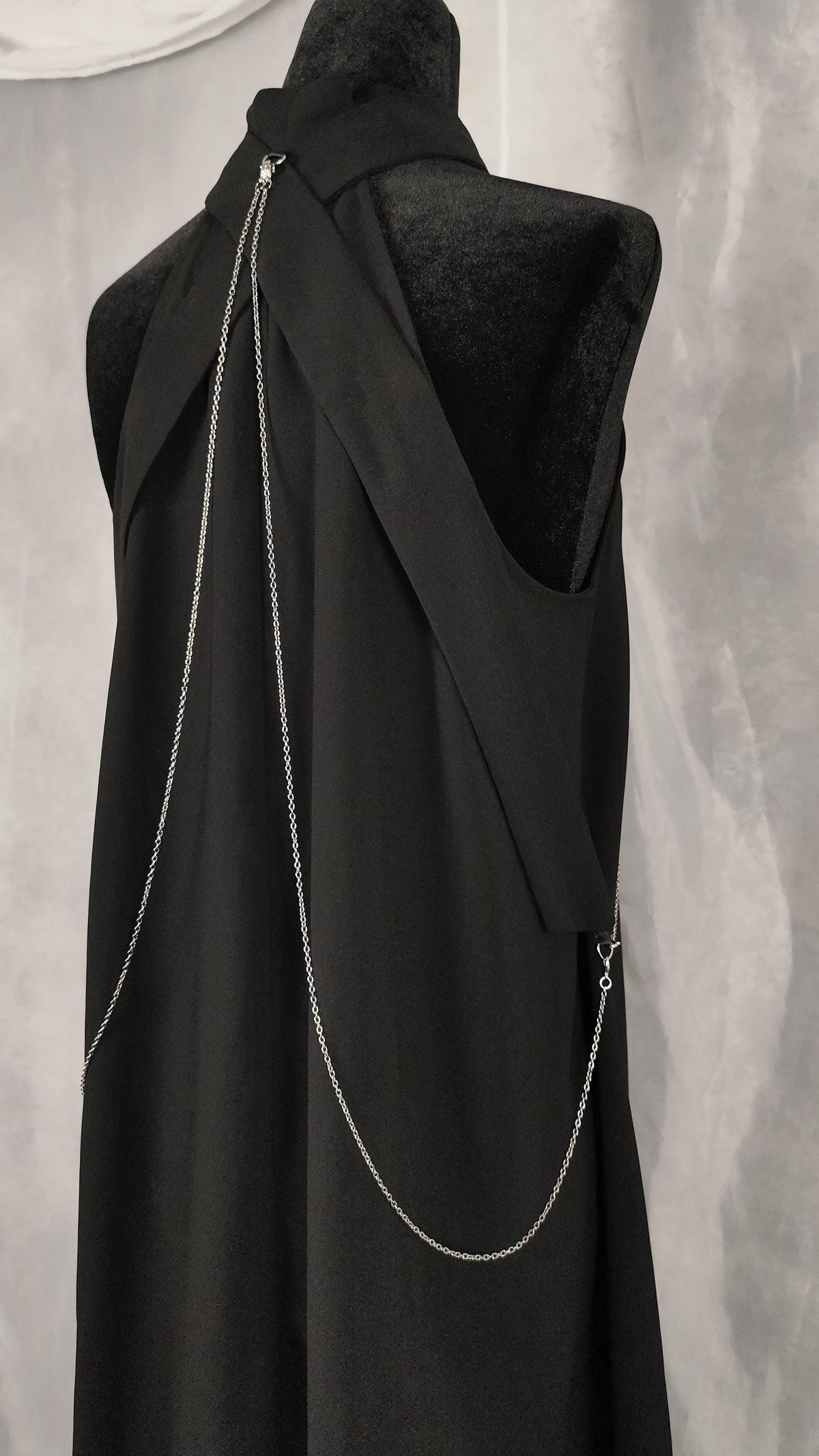 Close-up of the back of an elegant black tunic with straps and chains.