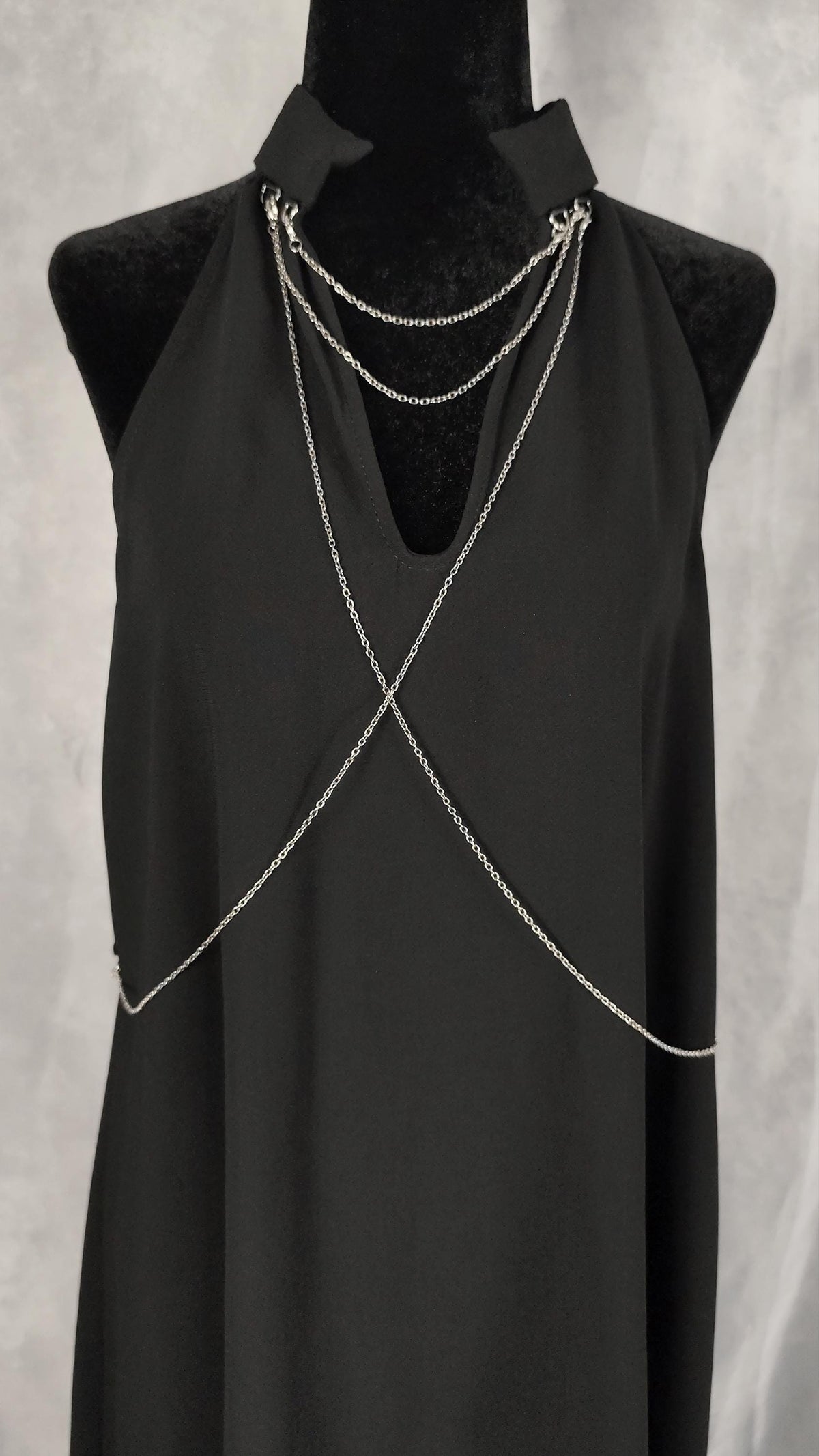 Close-up of the front of a black tunic with removable silver chains on the collar and chest to the back.
