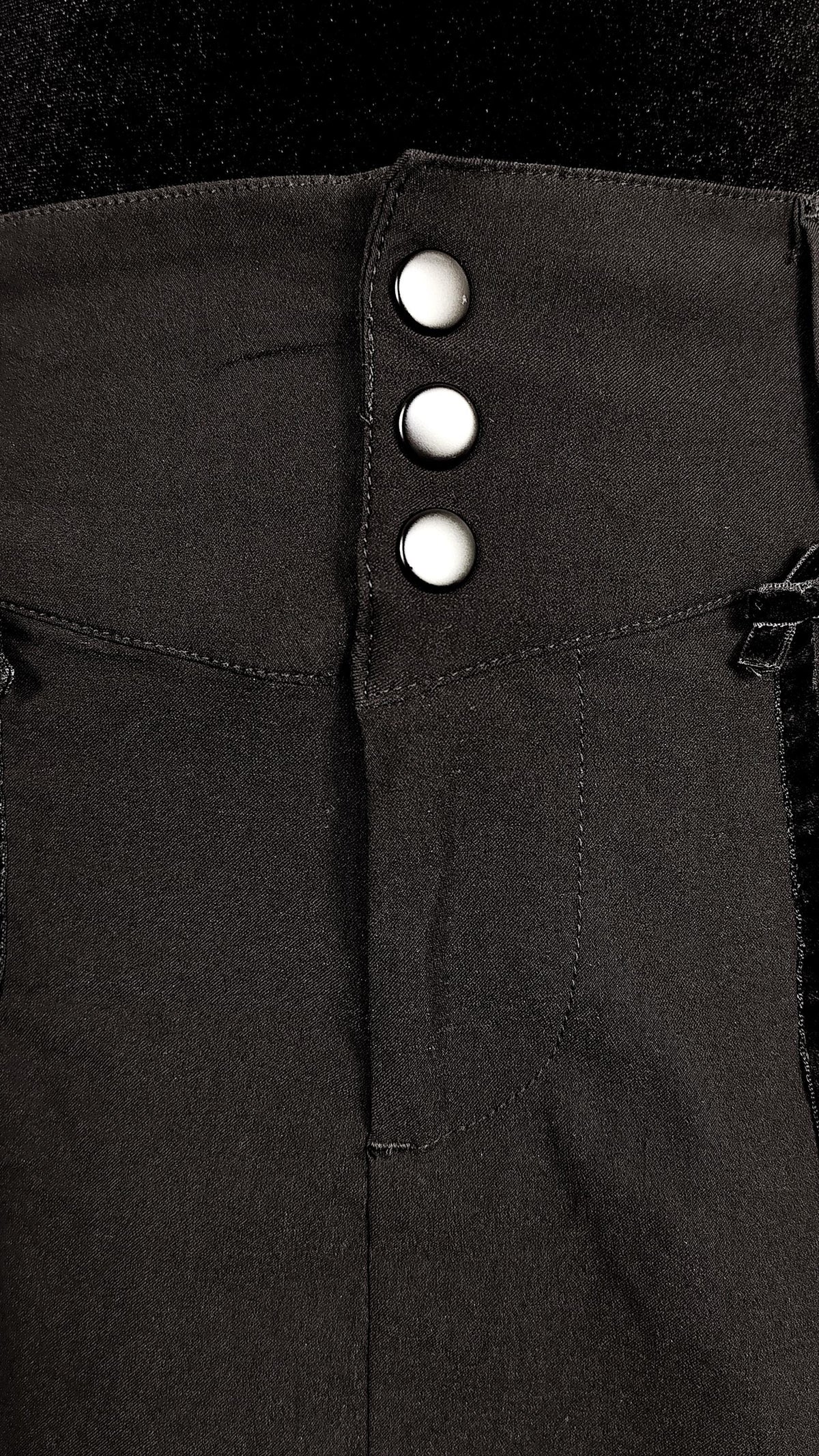 Close-up of a black skirt featuring three prominent black buttons aligned vertically on the front.