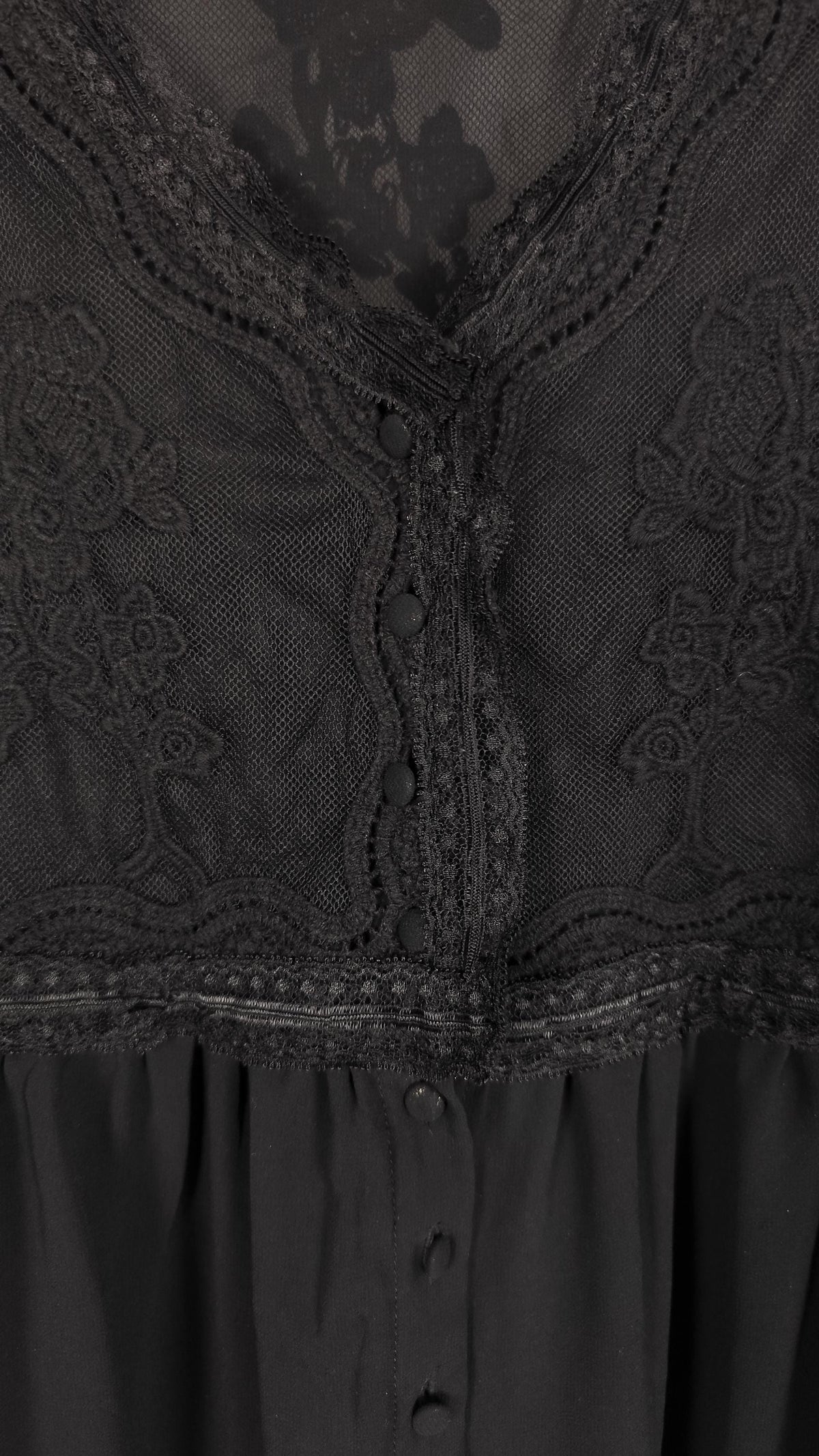 Close-up of a black lace and mesh midi dress with floral embroidery, scalloped edges, and a buttoned front.