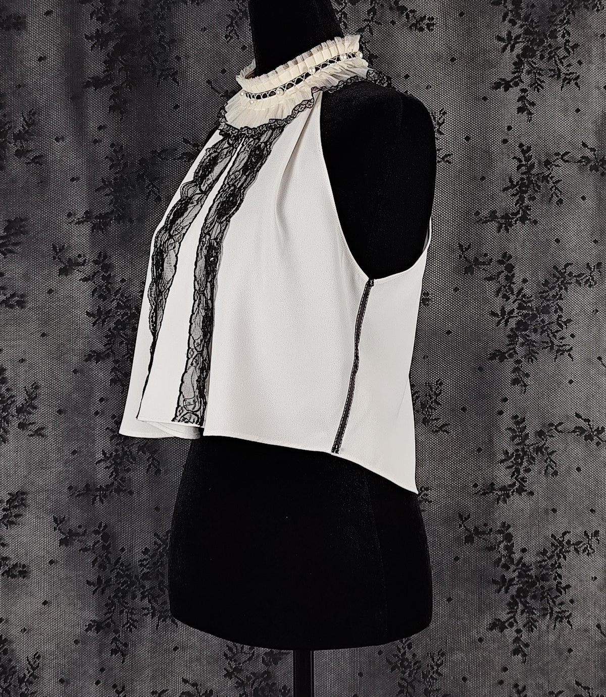 Side view of a Zara white sleeveless blouse transformed by Faceless Queen with black lace trim and a ruffled high neck.
