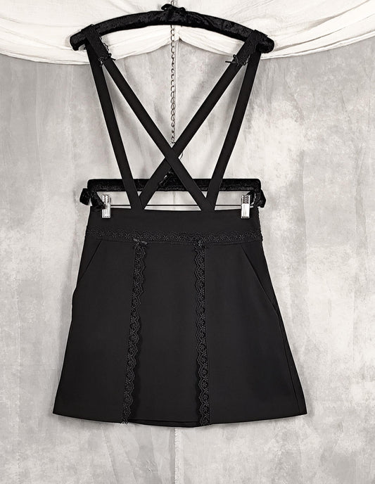 Front of high knee black skirt with removable straps and lace and satin bows details.