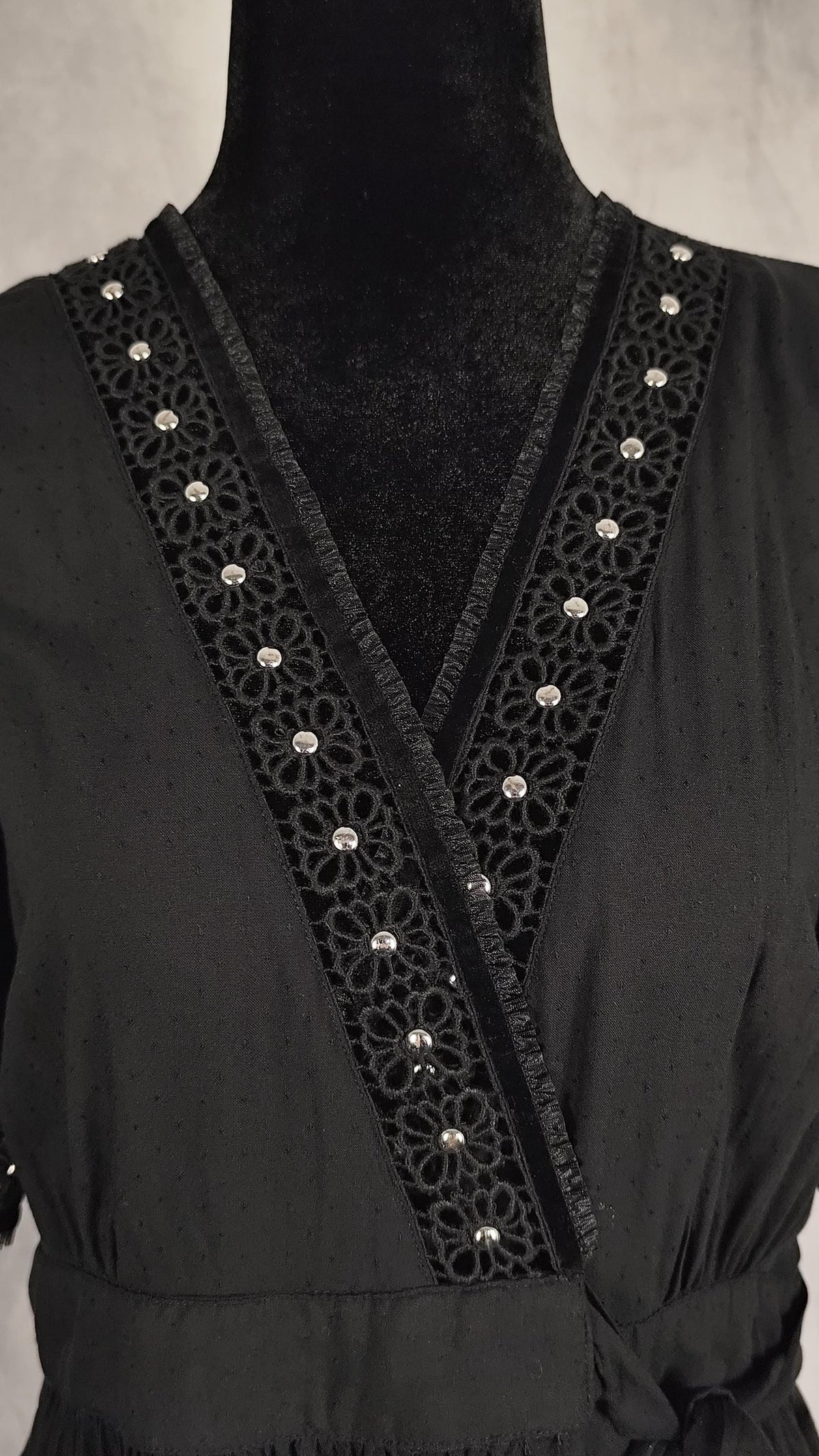 Decorative silver beaded trim along the V-neckline of black wrap dress.