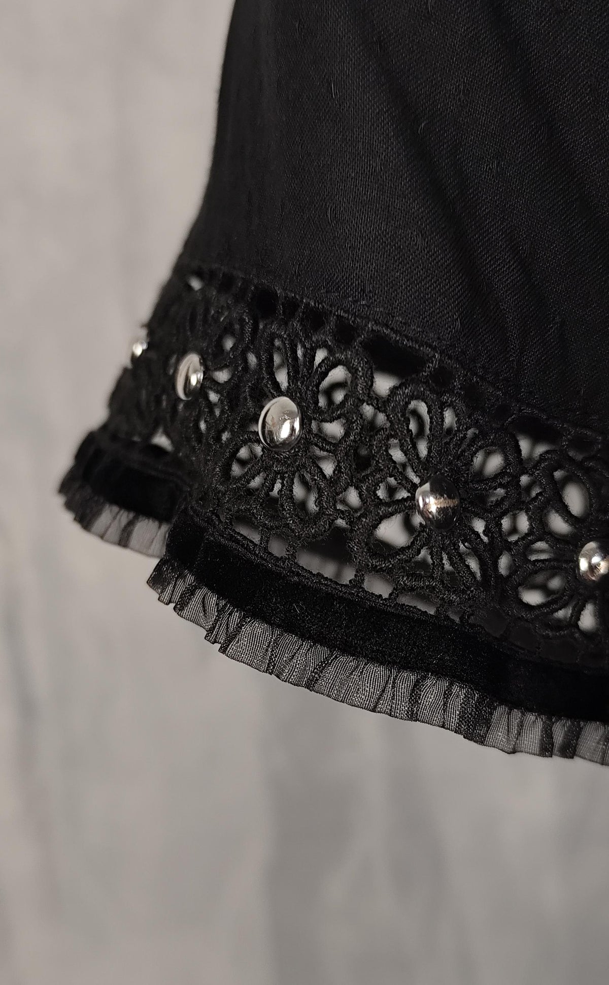 Detail of a decorative silver beaded trim along the sleeve cuffs, of black wrap dress.