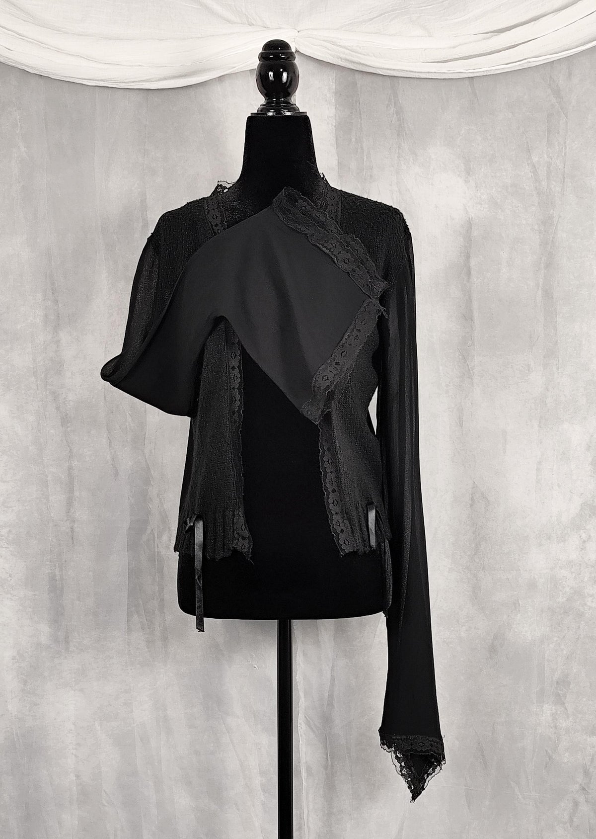 Composition to show the form from a sleeve of a black long-sleeve lace-trim cardigan for sale by Faceless Queen. 