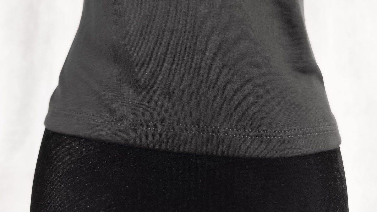 Close-up of a black t-shirt hem with a double-stitched edge, against a white background.
